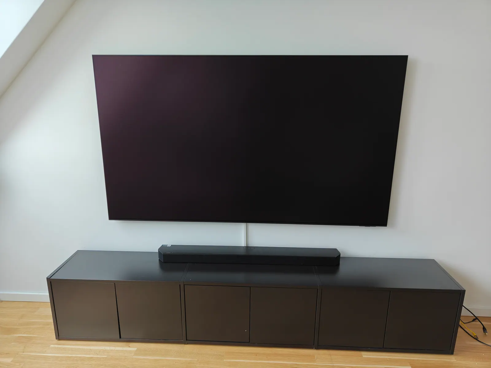 Wandmontierter Fernseher über schwarzem Sideboard mit Soundbar